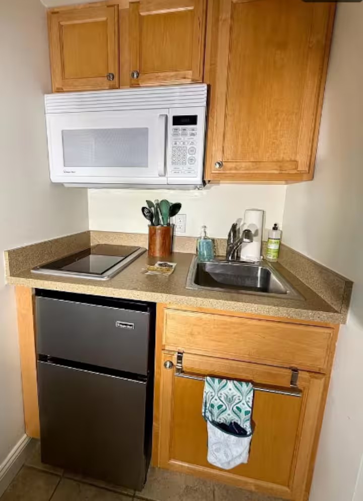 Compact kitchenette with cooktop, microwave, sink, and refrigerator