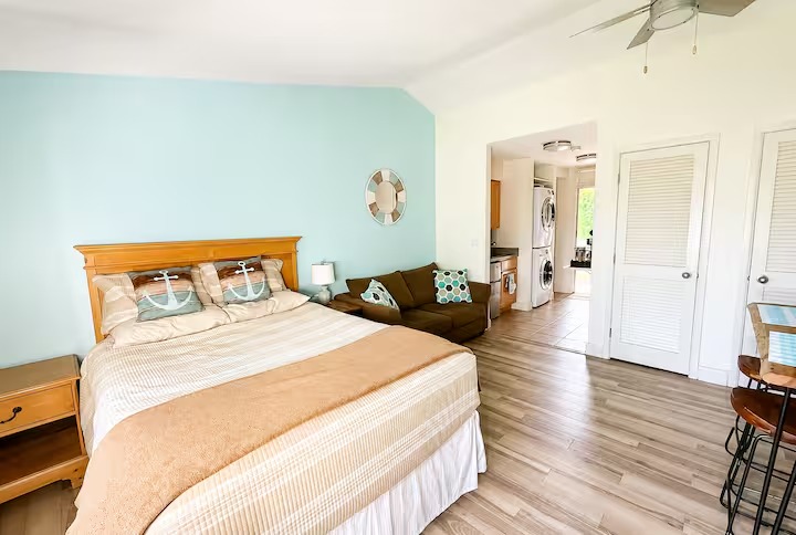 Bright open studio with a queen bed, sofa, and vaulted ceiling