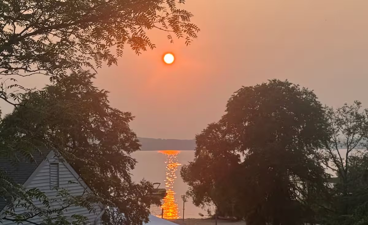 The sun setting over East Grand Traverse Bay, framed by trees